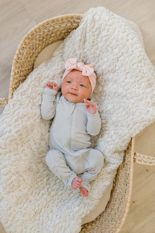 Baby Wearing Luna Luz Pajama Romper With Two-Way Zip in Stone Pictured With Bow Headband in Bubble Gum