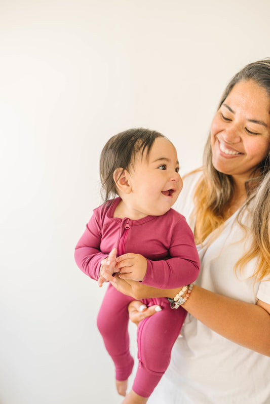 Baby Wearing Two-Way Zip Romper in Cranberry Being Held by Mother