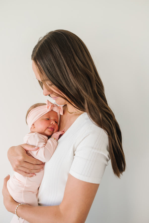 Baby Wearing Luna Luz Knotted Gown in Bubble Gum Being Held by Mother